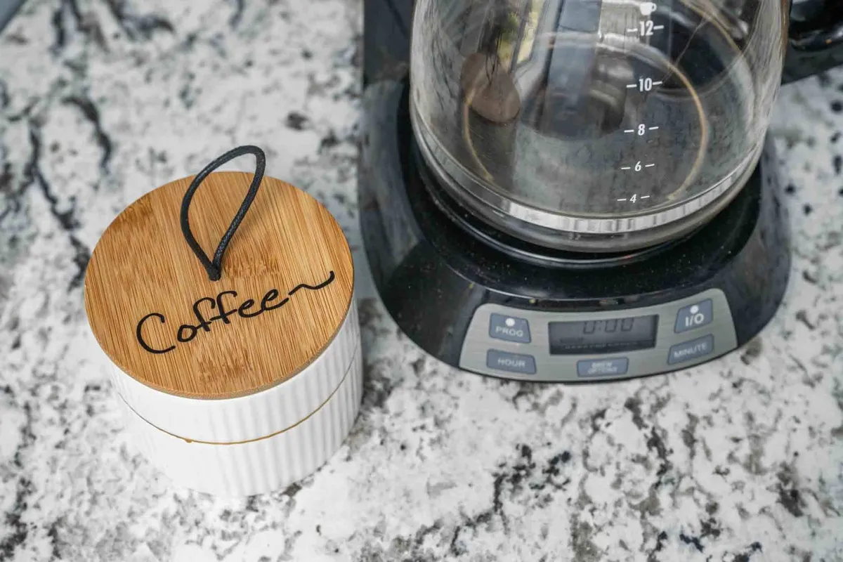 A close-up of a coffee maker and coffee container resting on a granite countertop, inviting guests to begin their day with a fresh brew or wind down with an afternoon cup.