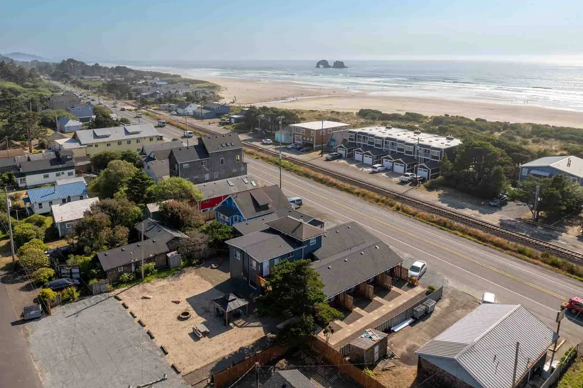 This image captures a beach view with the ocean, sandy shore, nearby houses, and a road leading toward the water. The scene evokes the proximity of the cottage to the coastline and highlights the ease of access to the beach, with the relaxed atmosphere and walkable neighborhood clearly visible.